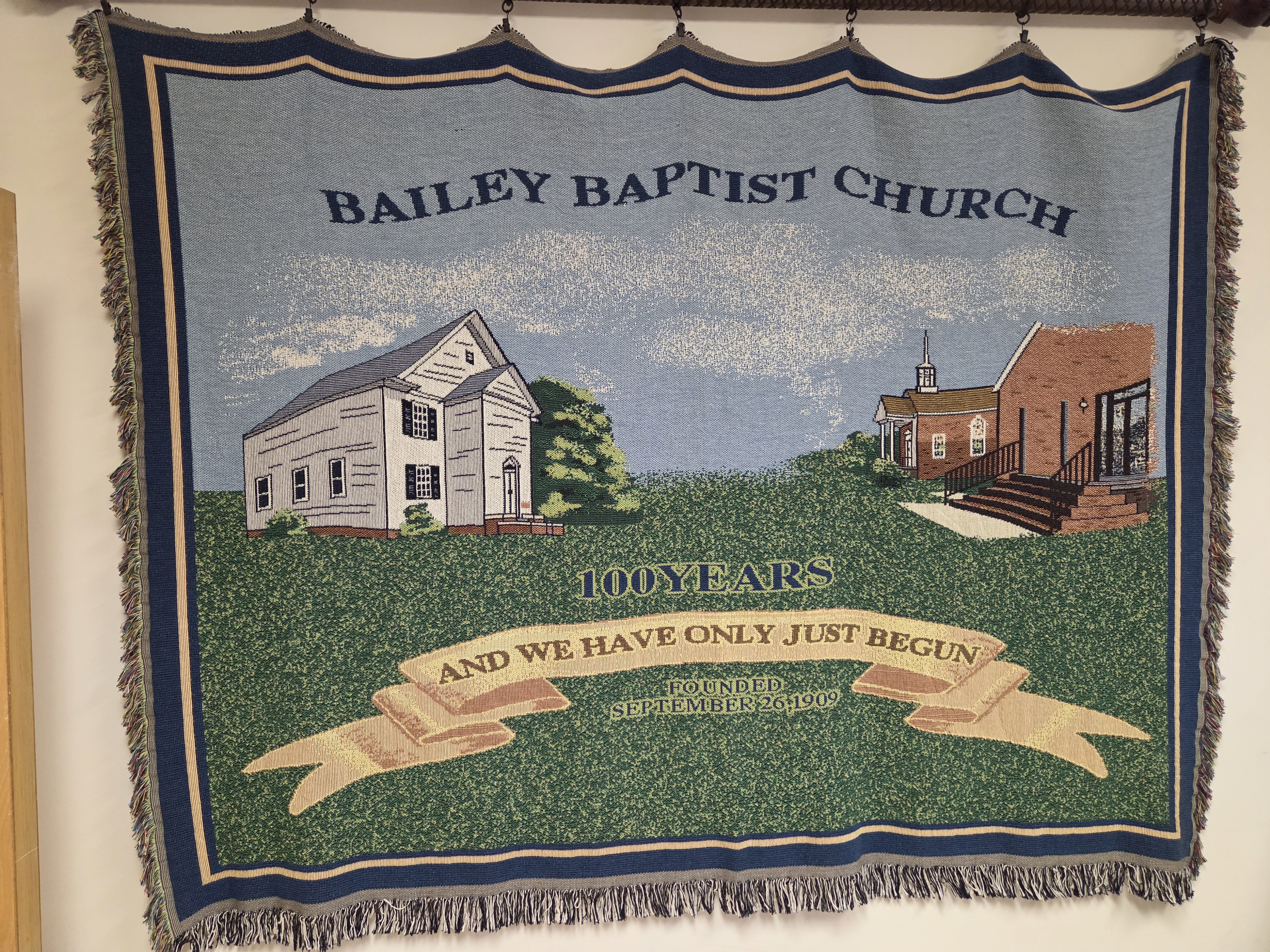 Centennial banner showing the original and present church buildings